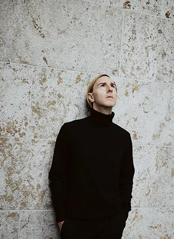 Il pioniere della musica elettronica Richie Hawtin appoggiato a un muro